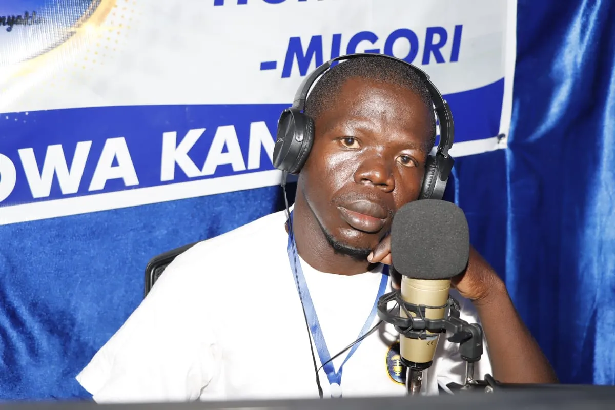 A presenter leaning towards the microphone in the studio, headphones on