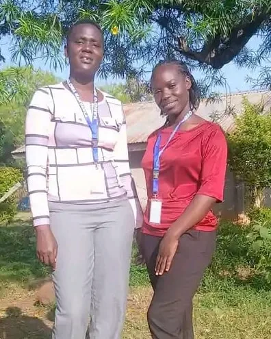 Two colleagues with staff badges standing under a tree